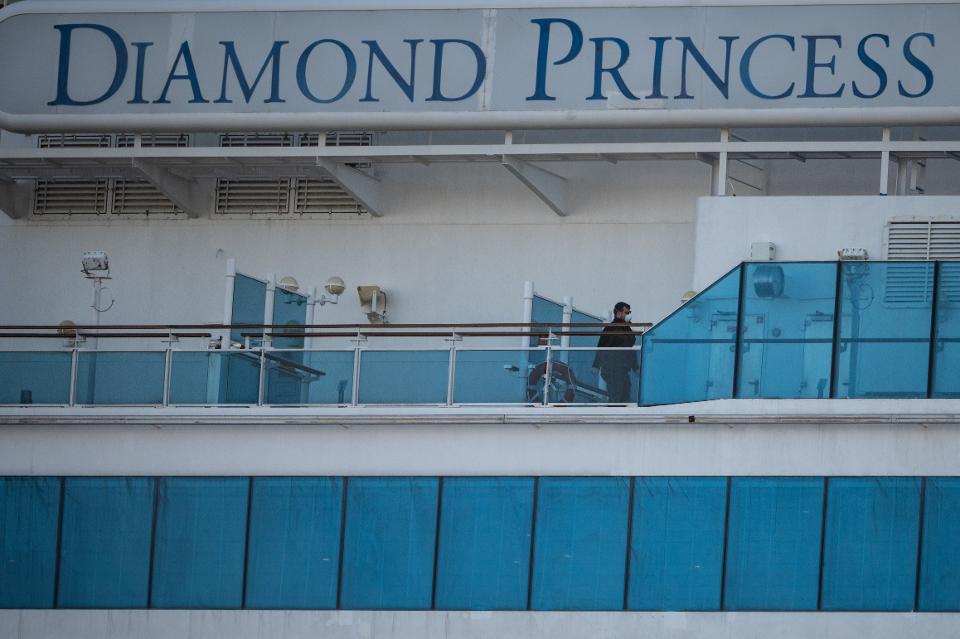 A crew member wearing a face mask walks on the deck of the Diamond Princess cruise ship at Daikoku pier cruise terminal in Yokohama on February 24, 2020.