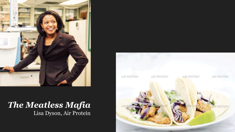 A Black woman in a brown suite smiling to the right and a seperate plate of tacos.